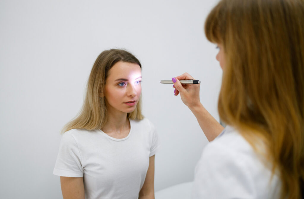 An eye doctor examining her patient's pupil reaction to light as part of an eye exam.