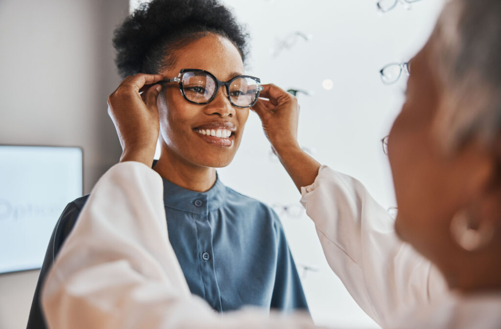 An optometrist carefully placing a newly prescribed pair of eyeglasses on a young lady, ensuring a precise fit for optimal vision correction.