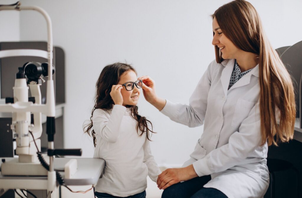  A child adjusts their glasses and smiles at their optometrist during an eye exam.