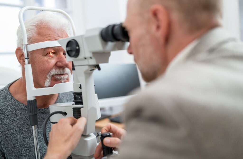 Older man receiving a comprehensive eye exam from an optometrist using a slit lamp in a clinical setting.