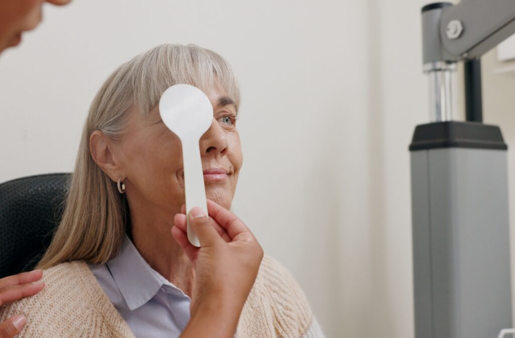 Senior woman undergoing a vision screening with one eye covered during a comprehensive eye exam.