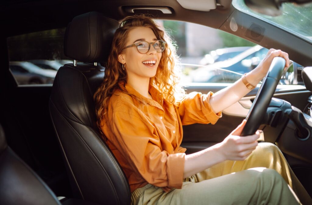 A cheerful person smiles while driving home after their routine eye exam appointment.