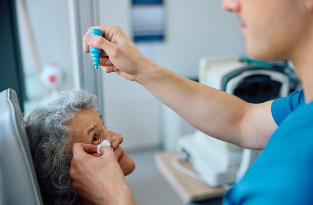 An optometric tech carefully administers a patient's dilation drops.