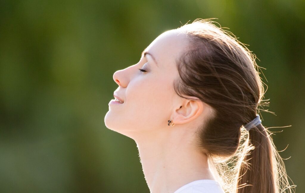A person standing outside tips their head back and enjoys the feeling of clear, moisturized eyes.