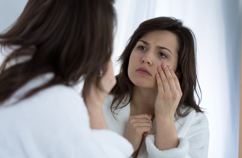 Person pulling the skin under their eye while looking into their eye in the mirror
