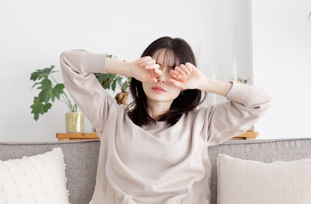 Person rubbing their eyes while sitting on the couch.