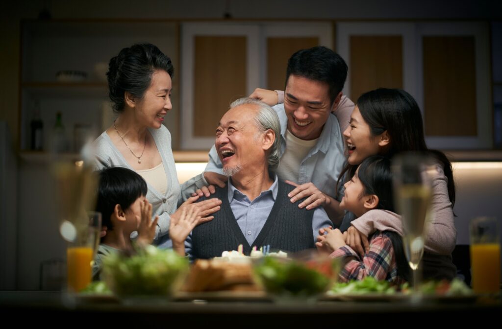 A family surrounds one senior family member and all are joyous