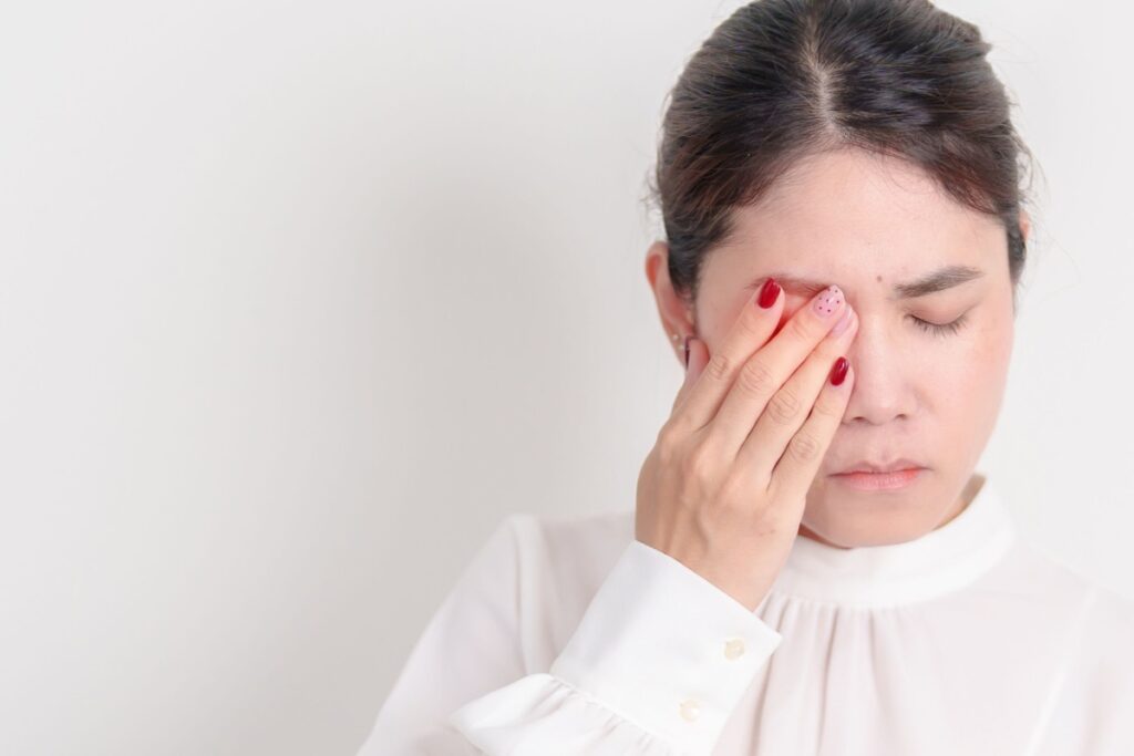 A person holding their eye that is irritated